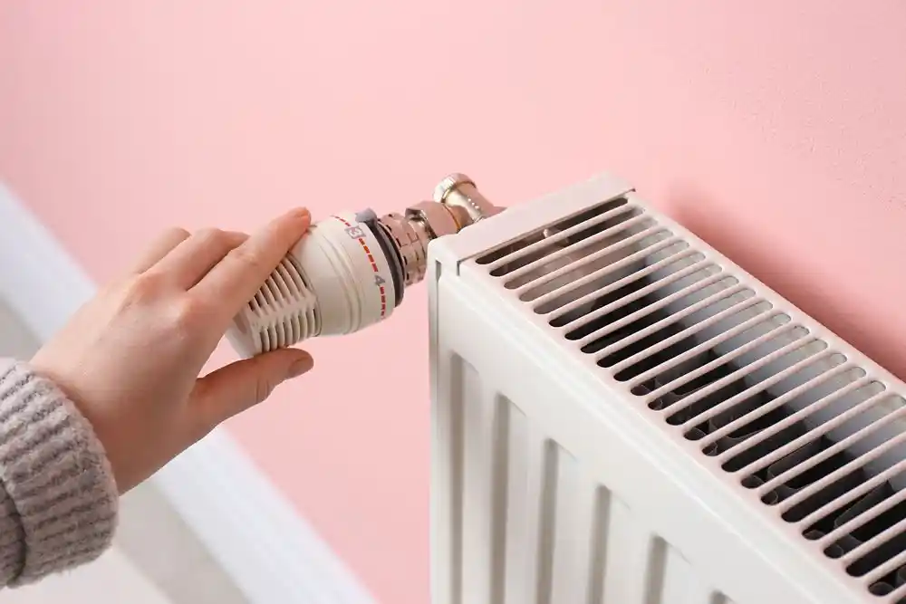 El, kalorifer peteğinin termostatını ayarlıyor