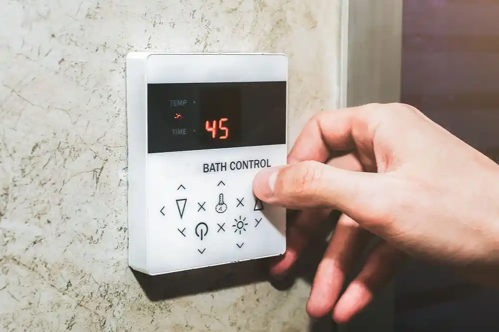 Bir el, ekranda 45 değeri görünen banyo kontrol panelindeki düğmeye basıyor