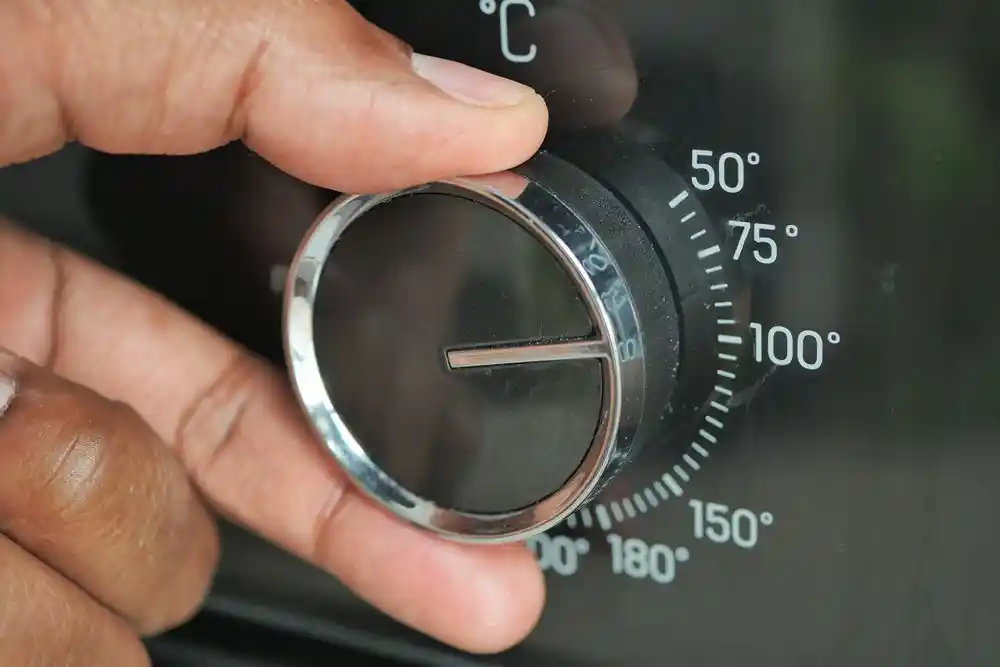 Bir el, sıcaklık ayar düğmesini çeviriyor; kadranda 50°–180° arası değerler görülüyor