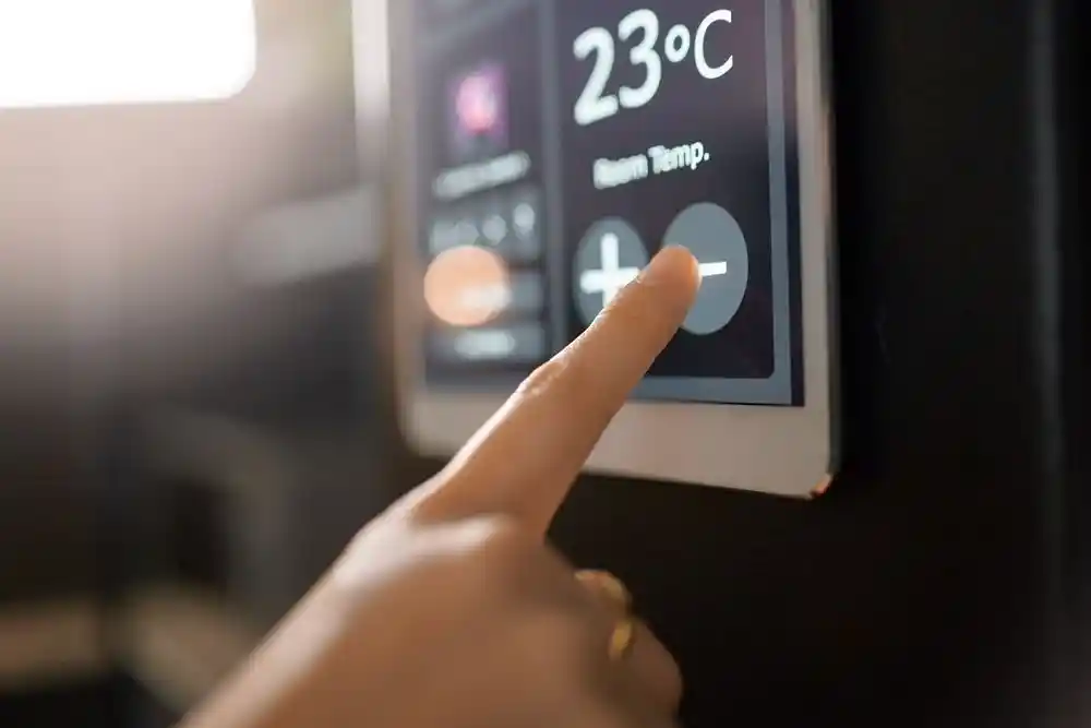 Bir parmak, 23°C gösteren termostatın sıcaklık azaltma düğmesine basıyor
